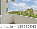 A well-designed balcony with a view of vibrant green trees and urban architecture in the background. Ideal for relaxation and enjoying nature in an urban setting. 136232543