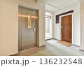 A sleek entrance hallway featuring an elevator and a wooden door, modern design elements, and smooth flooring create a welcoming atmosphere. 136232548