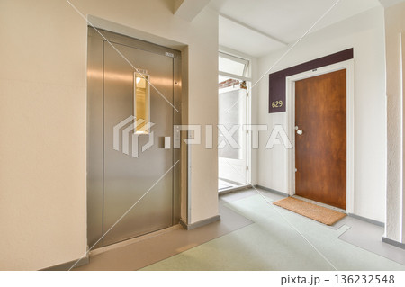 A sleek entrance hallway featuring an elevator and a wooden door, modern design elements, and smooth flooring create a welcoming atmosphere. A sleek entrance hallway featuring an elevator and a wooden door, modern design elements, and smooth flooring create a welcoming atmosphere. 136232548