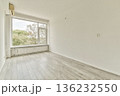 A spacious, uncluttered room featuring large windows that flood the space with natural light, showcasing a pale wooden floor and neutral walls. 136232550