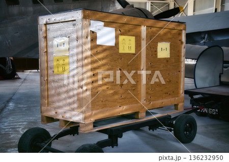 A large bulky wooden packing crate in an aircraft hangar, ready to be delivered by airplane A large bulky wooden packing crate in an aircraft hangar, ready to be delivered by airplane 136232950