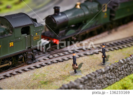 Close-up shot of miniature figures next to a model train track with detailed old-fashioned steam engine locomotives Close-up shot of miniature figures next to a model train track with detailed old-fashioned steam engine locomotives 136233169