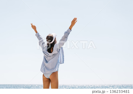 Woman Arms Beach: Woman raising arms toward clear sky, celebrating on sunny summer beach by sparkling sea. Woman Arms Beach: Woman raising arms toward clear sky, celebrating on sunny summer beach by sparkling sea. 136233481
