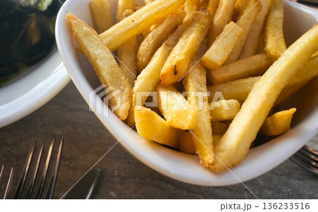 Close-up shot of a ceramic bowl full of french fries, or potato chips, as part of a fast-food restaurant meal 136233516