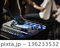 A man controlling the fader controls of a sound mixer backstage during a musical concert performance, with copyspace 136233532