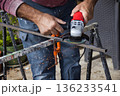 Close-up of the hands of a white Caucasian male holding an angle grinder to smooth the surface of a steel metal rod - home improvement do it yourself concept shot 136233541