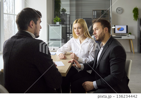 Financial advisor consulting couple clients during private meeting in office Financial advisor consulting couple clients during private meeting in office 136234442