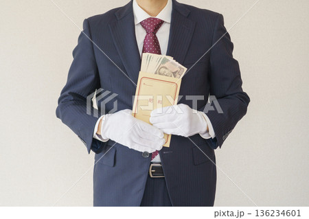 給料袋を持つスーツを着た男性｜一万円札の入った給料袋 136234601