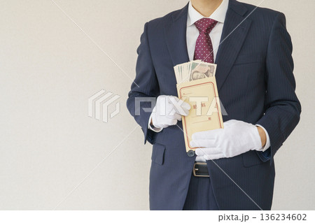 給料袋を持つスーツを着た男性|一万円札の入った給料袋 給料袋を持つスーツを着た男性|一万円札の入った給料袋 136234602
