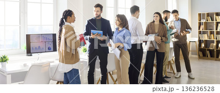 Diverse colleagues networking and discussing ideas in sunny open plan office space Diverse colleagues networking and discussing ideas in sunny open plan office space 136236528