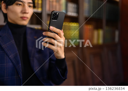 書斎でスマートフォンを見る知的で真剣な表情の日本人男性 136236834
