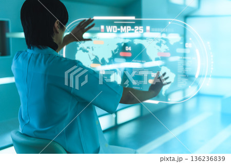 青い光の中でホログラフィックな世界地図を操作する研究者 青い光の中でホログラフィックな世界地図を操作する研究者 136236839