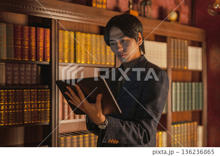 書斎でタブレットを操作するスーツ姿の日本人男性 136236865