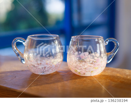木のテーブルに並ぶ手作り吹きガラスのペアカップ 136238194