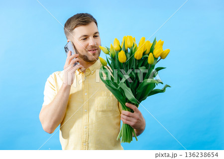 Man holding bouquet of flowers and cell phone 136238654