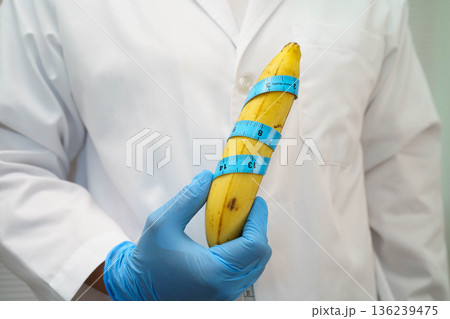 Male doctor stands holding a banana, penis health. 136239475