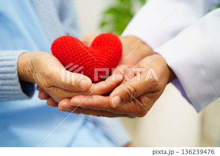 Asian elder senior woman patient holding red heart in hospital. 136239476