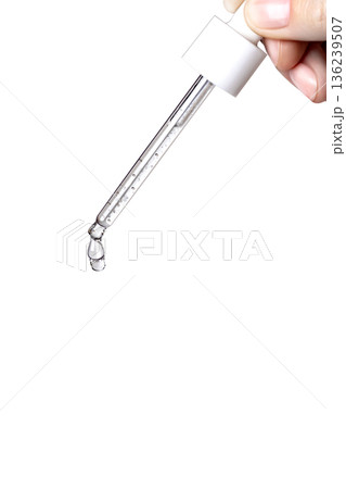 Pipette with serum in hand. Drips drop isolated on white background, copy space vertical photo close up 136239507