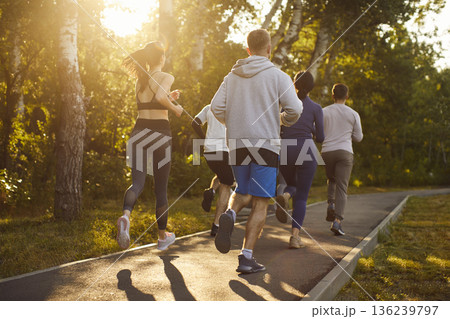 Runners training, young people running marathon together through green park 136239797