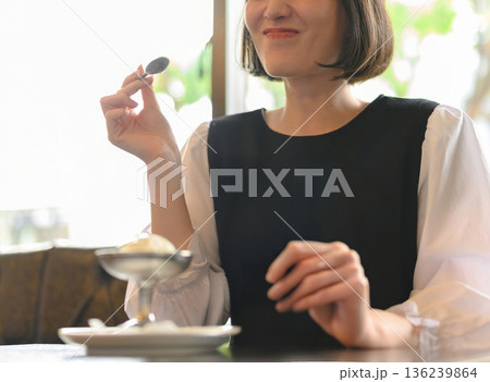カフェでアイスクリームを食べる笑顔の若い女性（上半身） 136239864