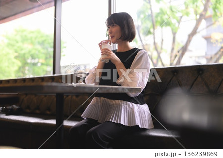 カフェの窓際で飲み物を飲む若い女性 136239869