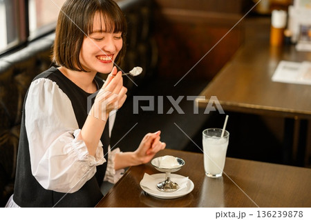 カフェでアイスデザートを食べる笑顔の若い女性 136239878