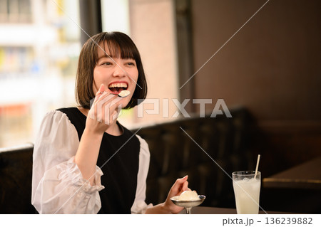 カフェでアイスクリームを食べる笑顔の若い女性 カフェでアイスクリームを食べる笑顔の若い女性 136239882
