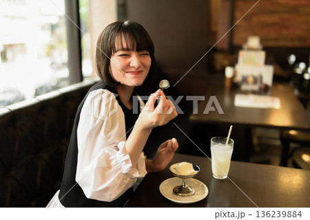カフェでアイスクリームを食べる笑顔の若い女性 136239884