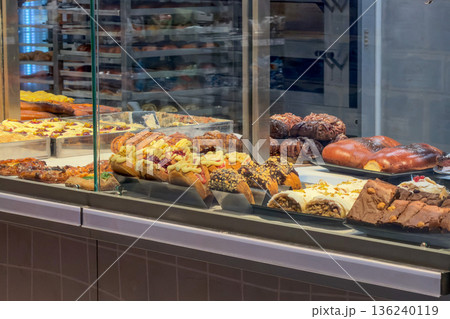 A vibrant bakery display case filled with enticing assortment of freshly baked pastries, sweet buns, and decadent desserts, showcasing delightful treats for hungry customers A vibrant bakery display case filled with enticing assortment of freshly baked pastries, sweet buns, and decadent desserts, showcasing delightful treats for hungry customers 136240119