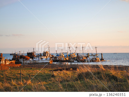 The photograph captures a striking view of a sea bay and a haunting ship graveyard on the Kuril Islands at sunset. 136240351
