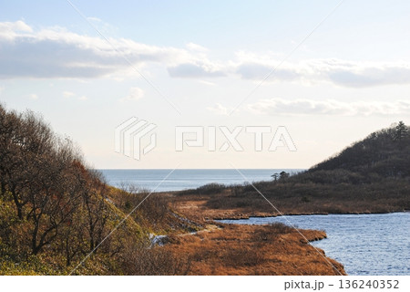 The photograph captures a breathtaking view of a sea bay and autumn forest on the Kuril Islands during sunset on a sunny day. The photograph captures a breathtaking view of a sea bay and autumn forest on the Kuril Islands during sunset on a sunny day. 136240352
