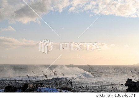The breathtaking coastline of a Kuril Islands bay glistens at sunset on a sunny winter day. 136240371