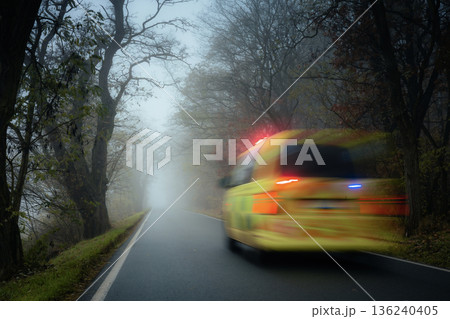 Emergency ambulance speeding on road in heavy fog on gloomy autumn day 136240405