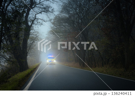 Emergency ambulance speeding on road in heavy fog Emergency ambulance speeding on road in heavy fog 136240411