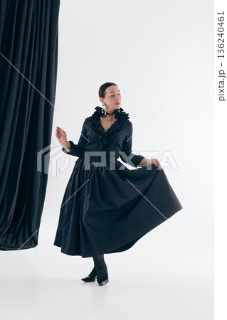 Black dress woman performing graceful studio pose with expressive confidence. Black dress woman performing graceful studio pose with expressive confidence. 136240461