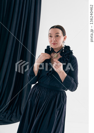 Elegant woman in black vintage dress adjusting necklace 136240462