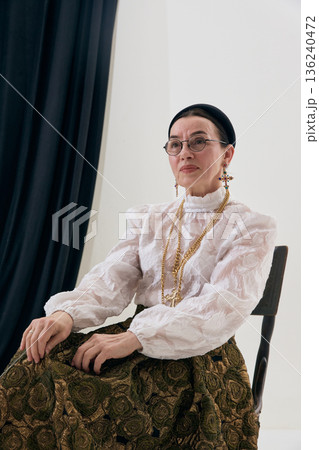 Classic retro fashion portrait with seated pose and refined expression. 136240472