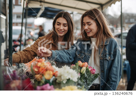 Two friends choosing fresh flowers at outdoor market in soft spring daylight 136240676