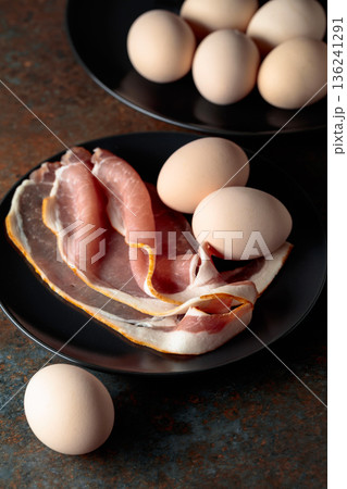 Smoked pork bacon with eggs on a black plate. 136241291