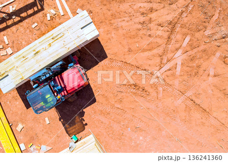 Tractor is transporting wooden planks at construction site scattered across 136241360
