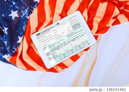 1040 tax form is displayed on digital PC tablet on American flag during federal tax time 136241362