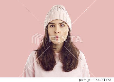 Portrait of funny young fashion model in pastel pink winter hat puckering her lips 136241578