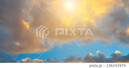 Radiant golden sunrise through dramatic clouds in a blue sky 136242974