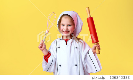 Child dressed as chef holding whisk and rolling pin. Child dressed as chef holding whisk and rolling pin. 136243388