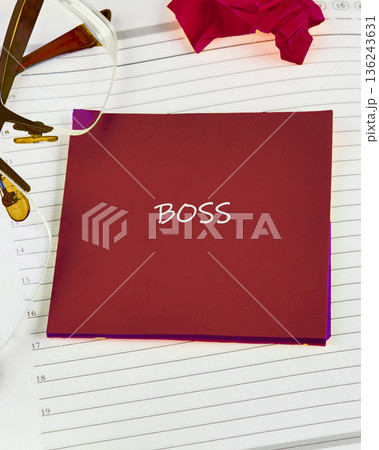 A bold red note with the word BOSS written in white is placed on an open notebook page 136243631