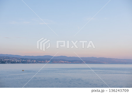 Coastal view of Opatija, Croatia, with calm Adriatic Sea and mountains in soft pastel evening light. Scenic seascape of Opatija, Croatia, city by the Adriatic Sea with distant hills and serene water. Coastal view of Opatija, Croatia, with calm Adriatic Sea and mountains in soft pastel evening light. Scenic seascape of Opatija, Croatia, city by the Adriatic Sea with distant hills and serene water. 136243709