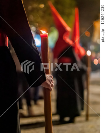 Detailed view of a hand holding a large lit candle in a religious procession 136244239