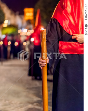 Detailed view of a hand holding a large lit candle in a religious procession Detailed view of a hand holding a large lit candle in a religious procession 136244242
