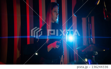 Female drummer playing live music with bright light 136244336