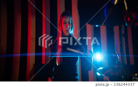 Female drummer playing cymbal in vibrant studio light Female drummer playing cymbal in vibrant studio light 136244337